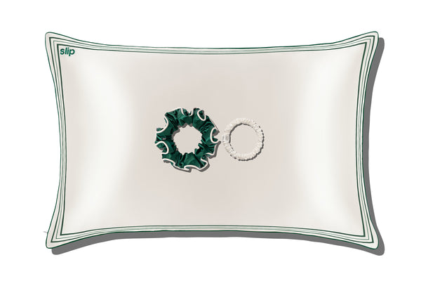 A white silk pillowcase, a green silk large scrunchie and a skinny white silk scrunchie on a white background