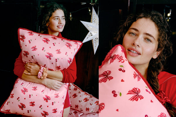 A split-screen lifestyle photo showing a woman holding a pink pillow with a red cherry and bow pattern. The left panel shows her holding the upright pillow, while the right panel is a close-up of the pillow's patterned fabric with lace trim.