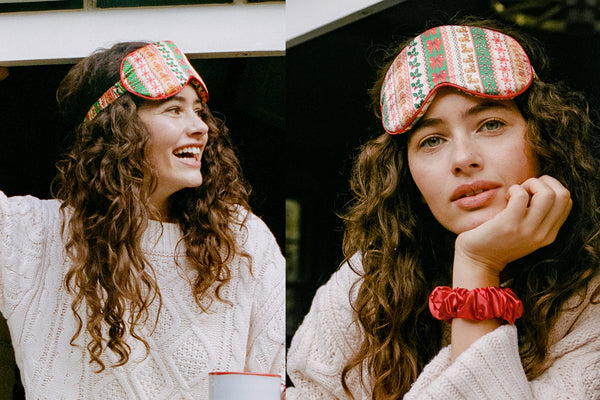 A split-screen lifestyle image showing a woman wearing a festive knit silk sleep mask and a red silk scrunchie. The contour sleep mask features a holiday pattern of red, green, and orange with bows and snowflakes, while she wears a white cable-knit sweater.
