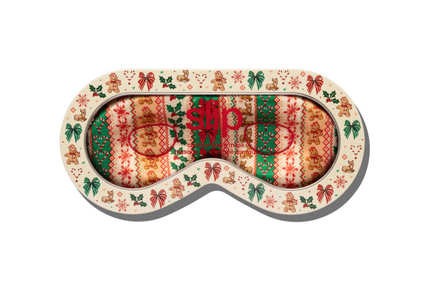 A festive Christmas-themed sleep mask tin packaging with a cream-colored border decorated with gingerbread men, candy canes, and holly, and a cozy knit-patterned center in red, green, and orange.