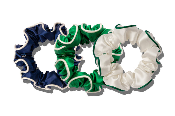Three scrunchies in navy, green, and white with contrasting piping on a white background