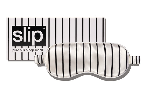 A black and white striped slip silk sleep mask with branded packaging on a white background.